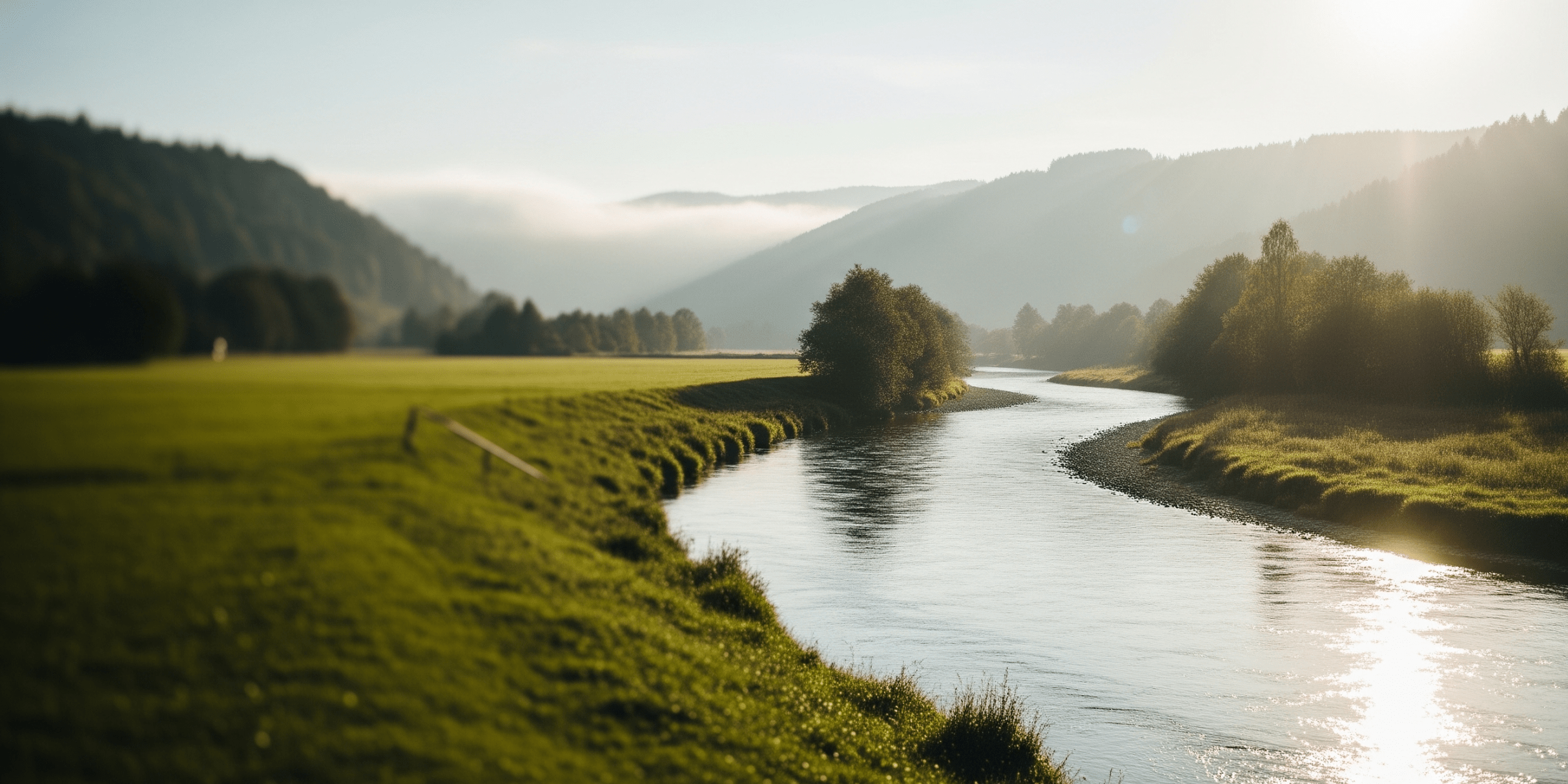 A winding river flowing through a lush green valley at sunrise, symbolizing the continuous and evolving customer journey towards business growth and strategic clarity.