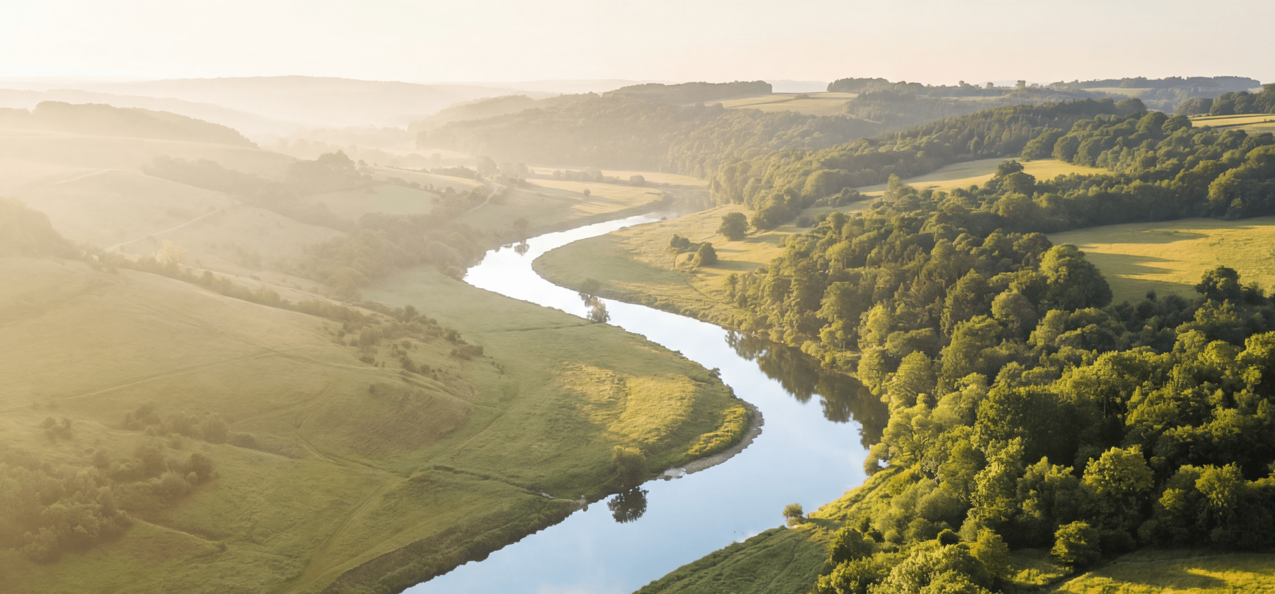 Fotorealističen panoramski posnetek reke, ki teče skozi zeleno pokrajino v jutranji svetlobi, kar simbolizira strukturiran tok in strateško jasnost nakupne poti stranke.